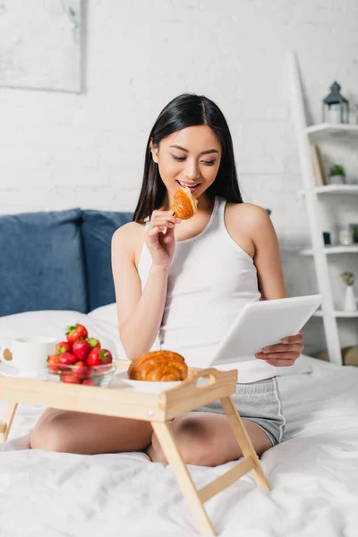 Enfoque Selectivo Chica Asiática Comer Croissant Uso Tableta Digital Durante — Foto de Stock