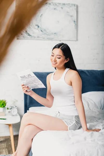 Selective Focus Smiling Asian Woman Reading Newspaper While Sitting Bed — Stock Photo, Image