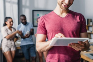 İş adamının arka planda iş arkadaşlarıyla dijital tablet kullandığı seçici odak 