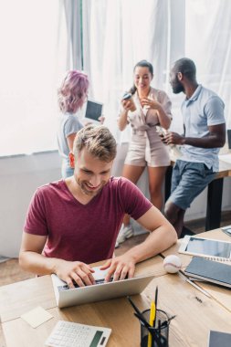 Dizüstü bilgisayar kullanan işadamlarının seçici odak noktası arka planda konuşan çok kültürlü meslektaşları. 