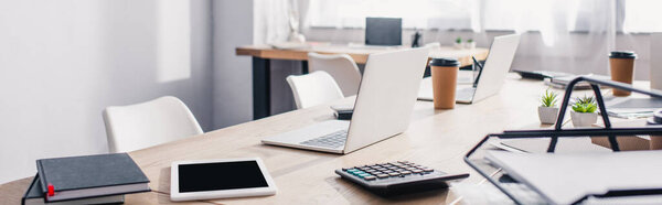 Panoramic shot of notebooks, calculator and digital devices on office table 