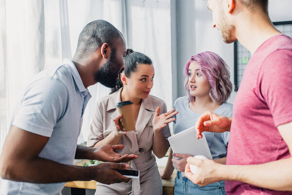 Селективный фокус мультикультурных бизнесменов, смотрящих на коллегу с цифровым планшетом в офисе 