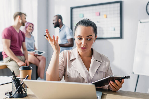 Selective focus of businesswoman holding clipboard and pen while working at table in office 