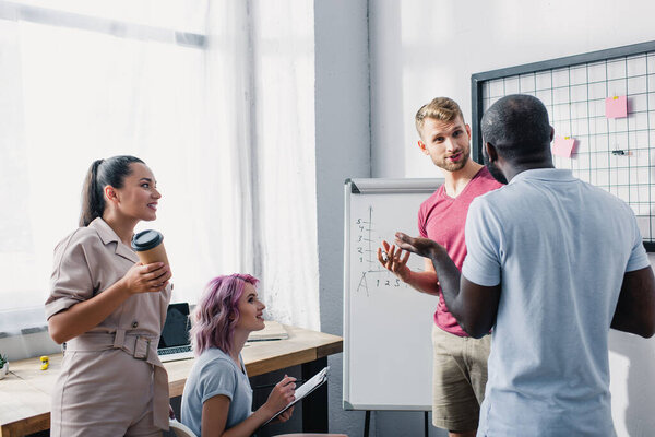 Selective focus of business people looking at african american colleague while working near whiteboard in office 