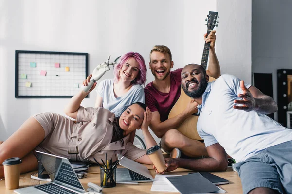 Multiethnische Geschäftsleute Mit Akustikgitarre Sitzen Neben Laptops Und Papieren Auf — Stockfoto