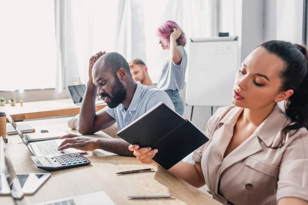 Selective Focus Businesswoman Holding Notebook African American Colleague Using Laptop — Stock Photo, Image