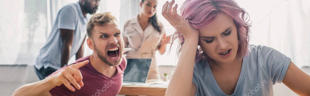 Panoramic crop of offended businesswoman near angry colleague screaming and pointing with finger in office 