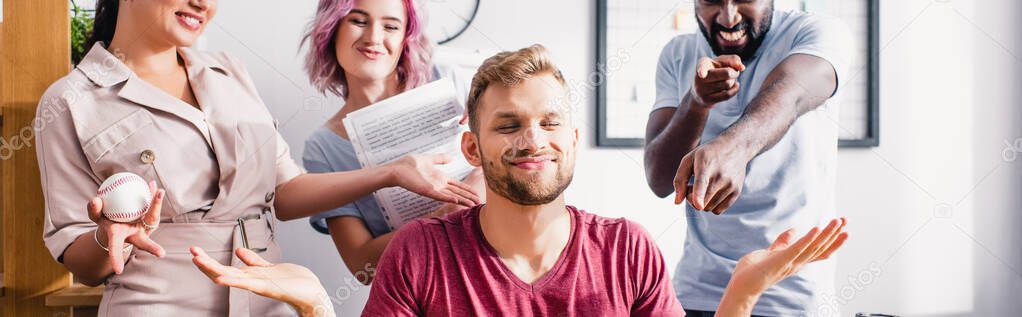 Panoramic shot of multiethnic business people pointing at colleague showing shrug gesture in office 