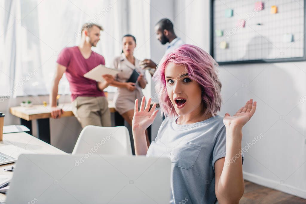 Selective focus of excited businesswoman looking at camera while working in office 