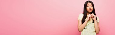Korkak Asyalı kızın panoramik mahsulü pembe kameraya bakıyor. 