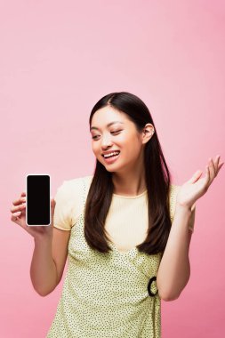 heyecanlı Asyalı kadın pembe ekranda boş ekranlı akıllı telefona bakıyor. 