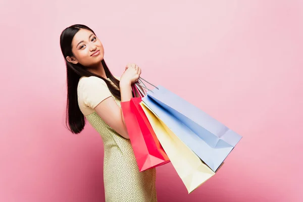 Asiatisches Mädchen Schaut Die Kamera Während Einkaufstüten Auf Rosa Hält — Stockfoto