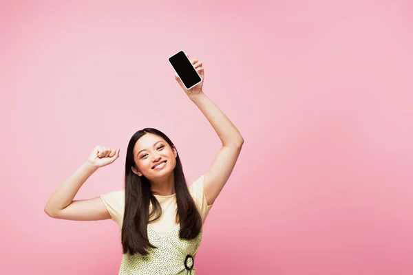 Улыбающаяся Азиатская Девушка Сжатым Кулаком Держащая Смартфон Пустым Экраном Изолированным — стоковое фото