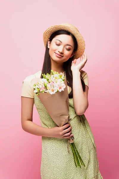 Felice Ragazza Asiatica Toccando Cappello Paglia Tenendo Bouquet Fiori Isolati — Foto Stock