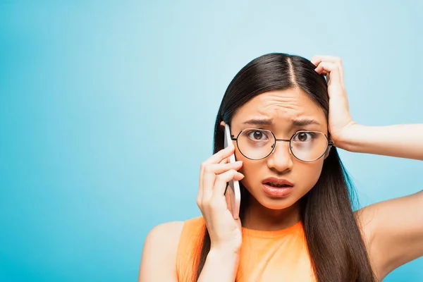 Confused Asian Girl Glasses Talking Smartphone Touching Head Blue — Stock Photo, Image