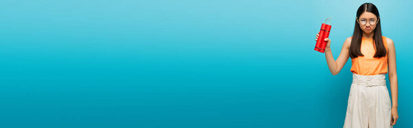 заголовок сайта недовольной азиатской девушки в очках с динамитовыми палочками на синем