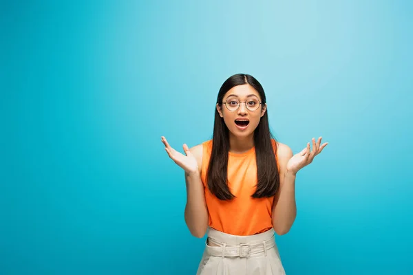Excited Asian Woman Glasses Gesturing Looking Camera Blue — Stock Photo, Image