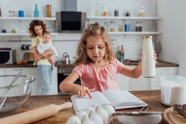 Selective Focus Girl Holding Bottle Milk While Reading Cookbook Mother — Stock Photo, Image