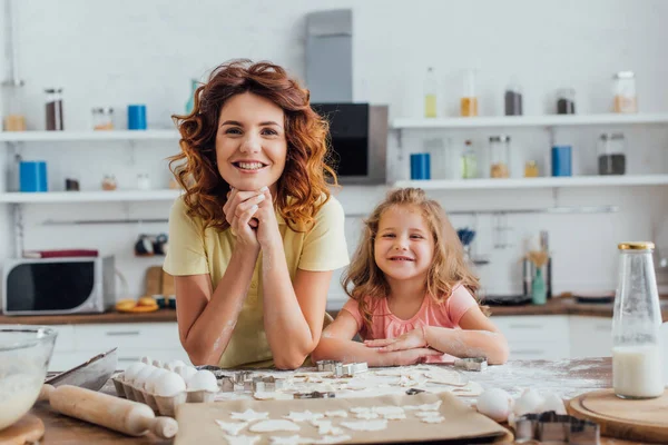 Joven Madre Hija Mirando Cámara Cerca Galletas Crudas Ingredientes Mesa — Foto de Stock