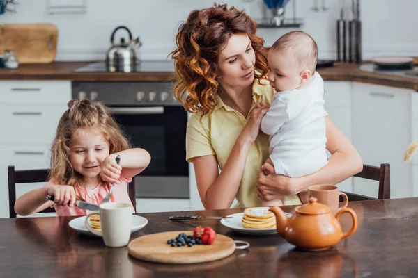 Selective Focus Mother Holding Infant Son Daughter Eating Pancakes — Stock Photo, Image