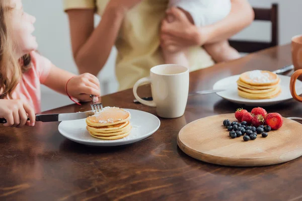 Cropped View Mother Holding Infant Son Daughter Eating Delicious Pancakes — Stock Photo, Image