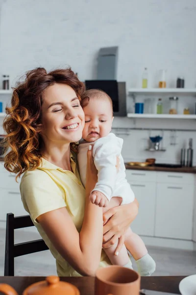 Selective Focus Young Mother Closed Eyes Holding Infant Boy Kitchen — Stock Photo, Image