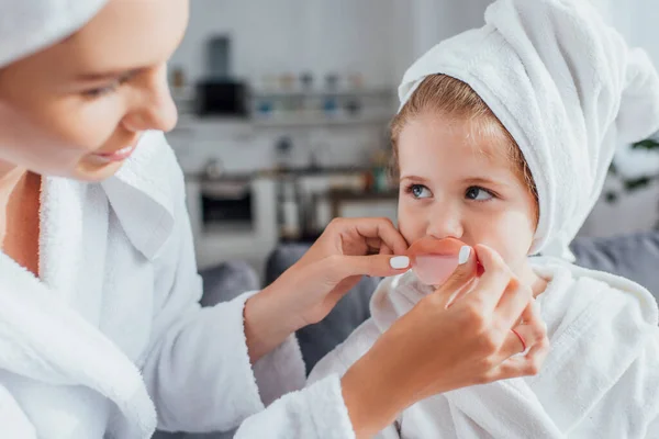 Selective Focus Woman Applying Lips Patch Daughter White Towel Head — Stock Photo, Image