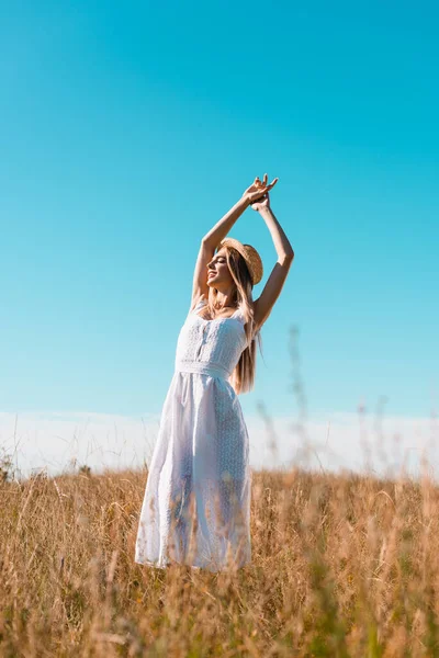 白いドレスを着たスタイリッシュな女性が手を挙げ青い空を背景に草原で目を閉じた — ストック写真