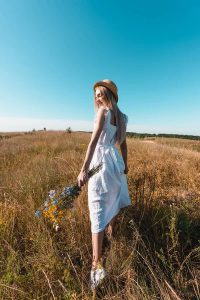 Young Woman White Dress Straw Hat Walking Grassy Meadow Bouquet — Stock Photo, Image