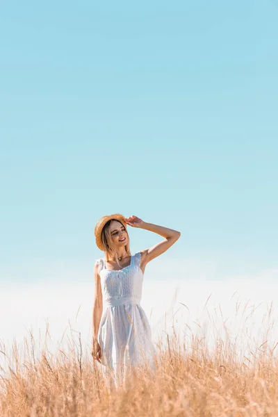 Jovem Mulher Vestido Branco Colina Gramada Tocando Chapéu Palha Olhando — Fotografia de Stock