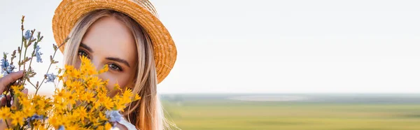 Panoramabild Blond Kvinna Halmhatt Som Håller Vilda Blommor Och Tittar — Stockfoto