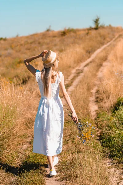 Visão Traseira Jovem Mulher Vestido Branco Tocando Chapéu Palha Enquanto — Fotografia de Stock