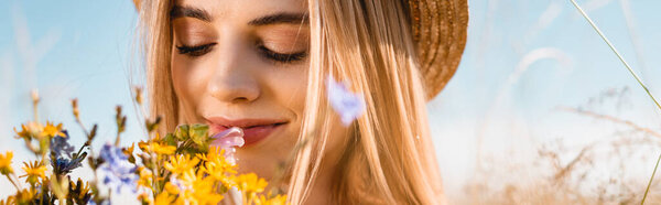 website header of sensual blonde woman smelling bouquet of wildflowers, selective focus