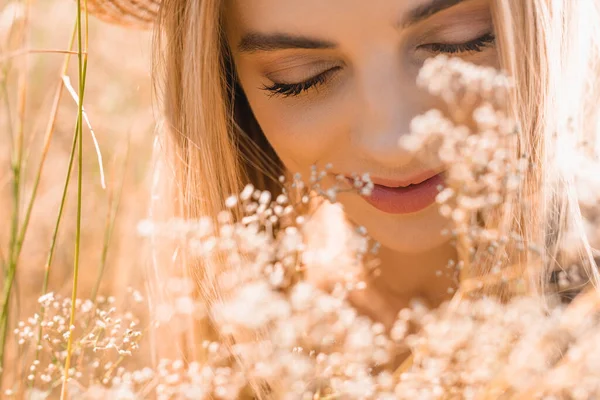 野の花の近くに目を閉じたブロンドの女性の肖像 — ストック写真