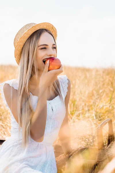 Selective Focus Blonde Woman Straw Hat Eating Ripe Apple Looking — Stock Photo, Image