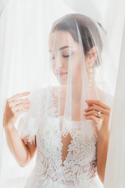 Gelinin seçici odağı gelinlik içinde duvağa dokunuyor 