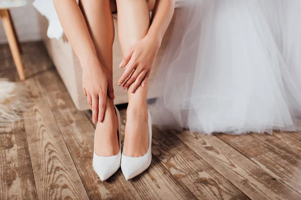 Обрезанный Вид Невесты Касающихся Ног Свадебных Каблуках Рядом Платьем Кровати — стоковое фото