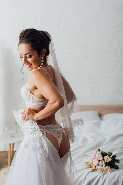 Junge Braut Dessous Und Schleier Trägt Hochzeitskleid Neben Strauß Auf — Stockfoto