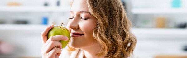 panoramic crop of woman with closed eyes smelling apple
