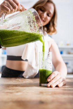 selective focus of woman pouring green smoothie in glass  clipart