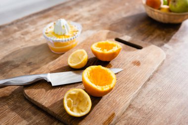 selective focus of squeezed orange halves near knife and juicer  clipart
