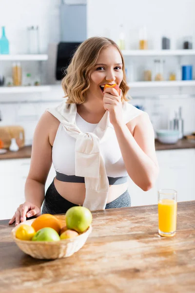 Mulher Comendo Pêssego Fresco Enquanto Olha Para Câmera Cozinha — Fotografia de Stock