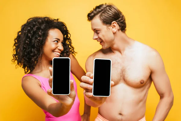 Mujer Afroamericana Rizada Hombre Sin Camisa Mirándose Mientras Muestra Teléfonos —  Fotos de Stock