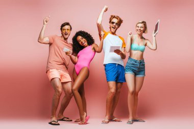 Heyecanlı, çok kültürlü, yaz kıyafetli arkadaşlarımız ellerinde pembenin üzerinde aletler tutarken birinci sınıf bir jest yapıyorlar.