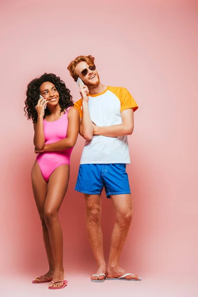 Multiethnic Couple Sunglasses Swimsuit Talking Smartphones Pink Background — Stock Photo, Image