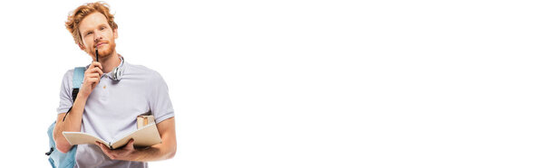 Panoramic shot of student holding pen and notebook while looking at camera isolated on white