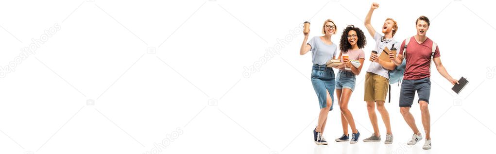 Panoramic shot of multiethnic students holding books and coffee to go on white background