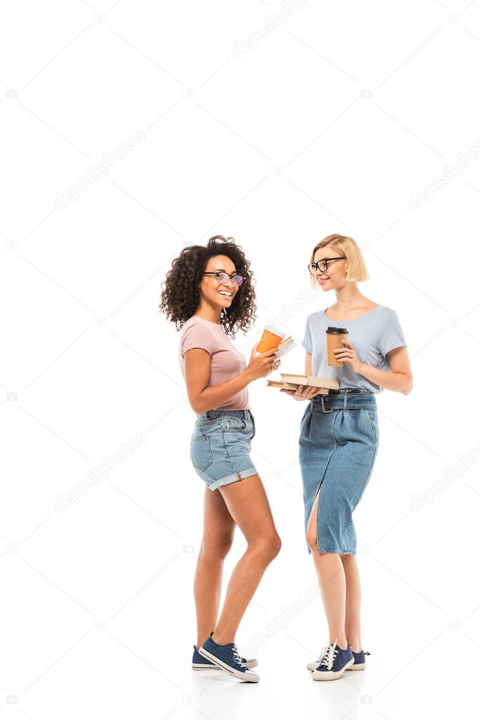 Multiethnic students with disposable cups and books on white background