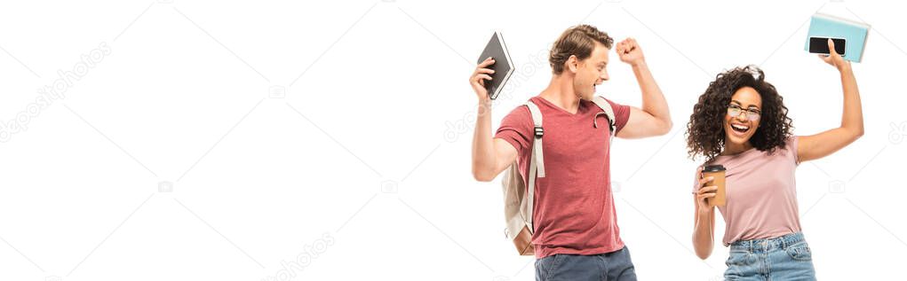 Panoramic shot of multicultural students with books, smartphone and coffee to go showing yes gesture isolated on white