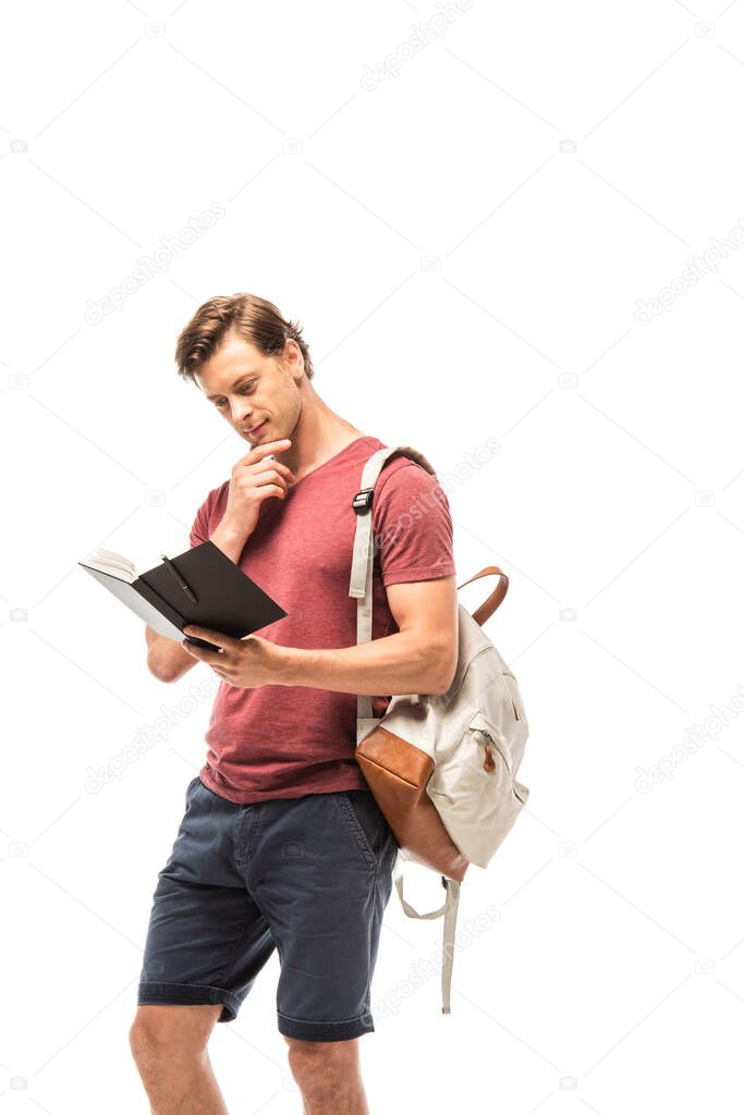 Pensive student with backpack looking at notebook isolated on white
